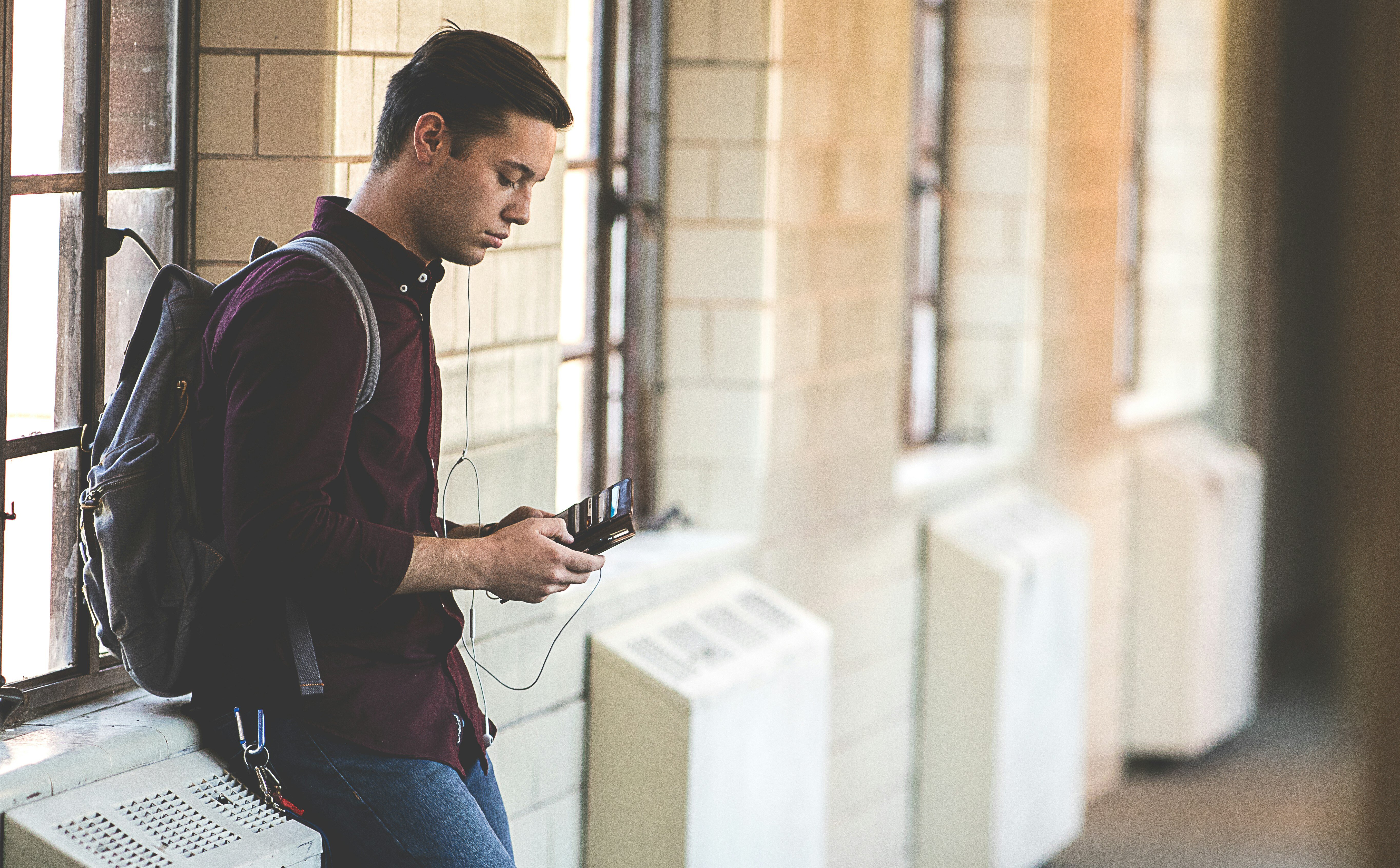 Student checking his phone against a wall